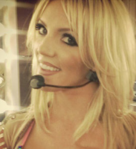 Britney Spears Celebrity Impersonator with blond shoulder length hair wearing a ear piece microphone.